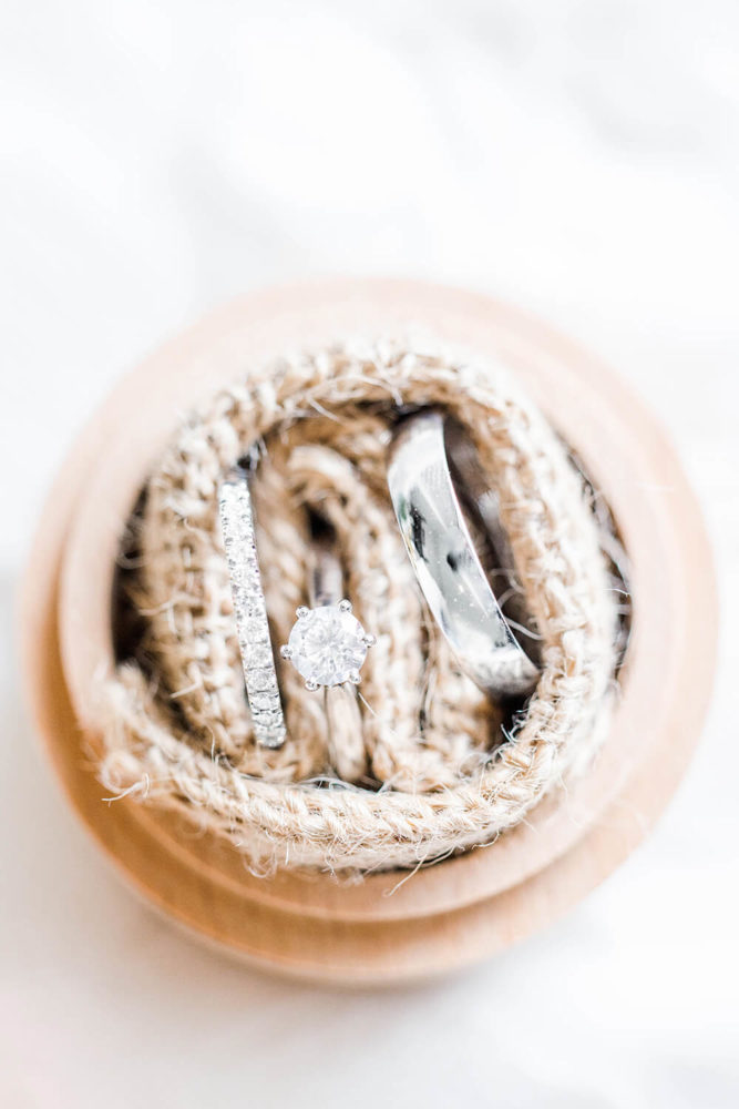 White gold wedding rings and solitaire round cut diamond ring in a wooden box