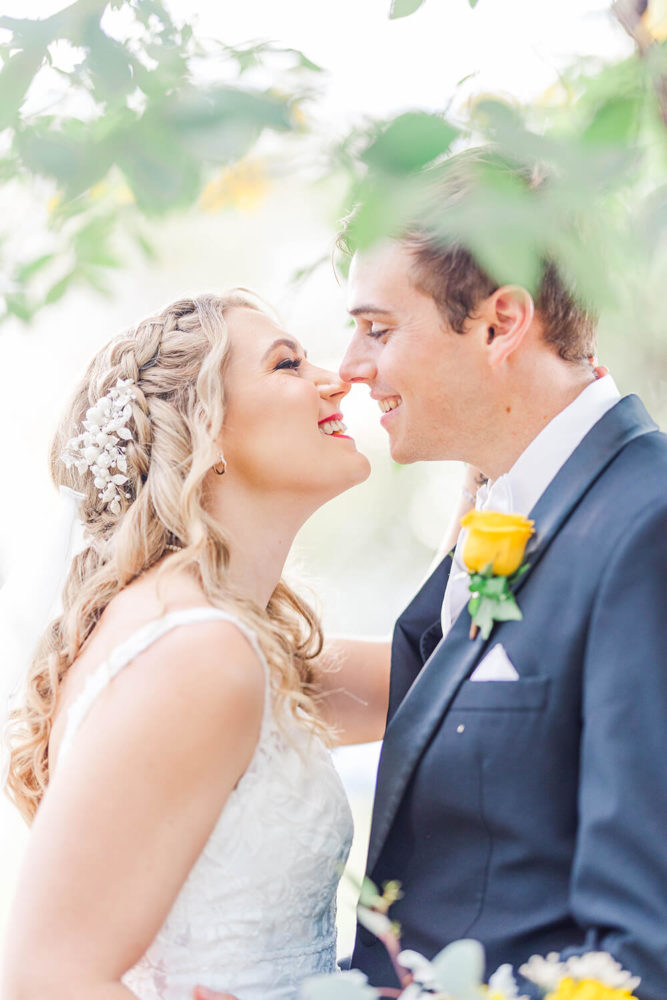 medium close up of a bride and groom under a tree staring lovingly at each other