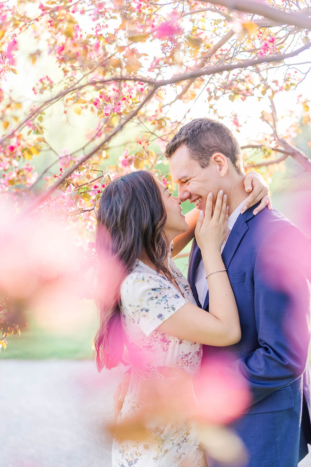 chinese young woman has her hand on the face of her lover in a navy blue jacket as he holder her in an embrance
